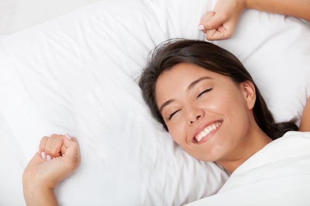 Beautiful woman awakening in her white bed and yawning.jpeg