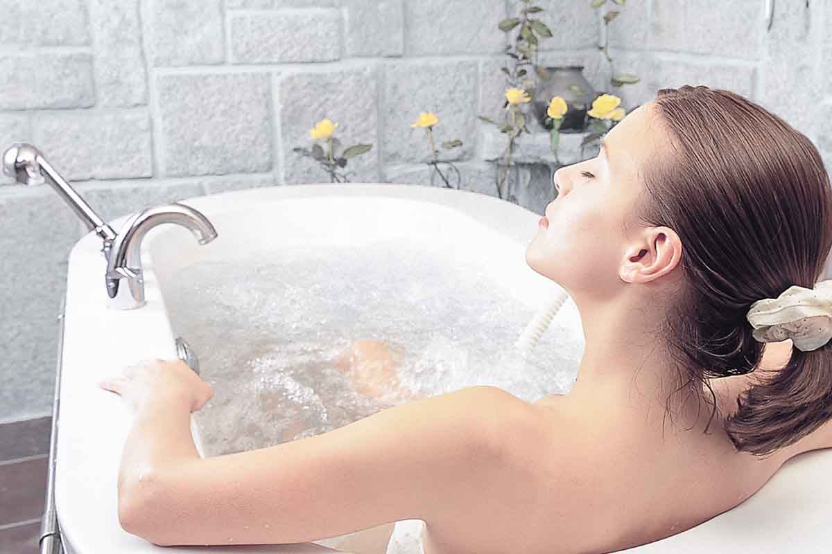 A woman who is enjoying a relaxing bath which is created by not only proper water temperature but also nice equipment.