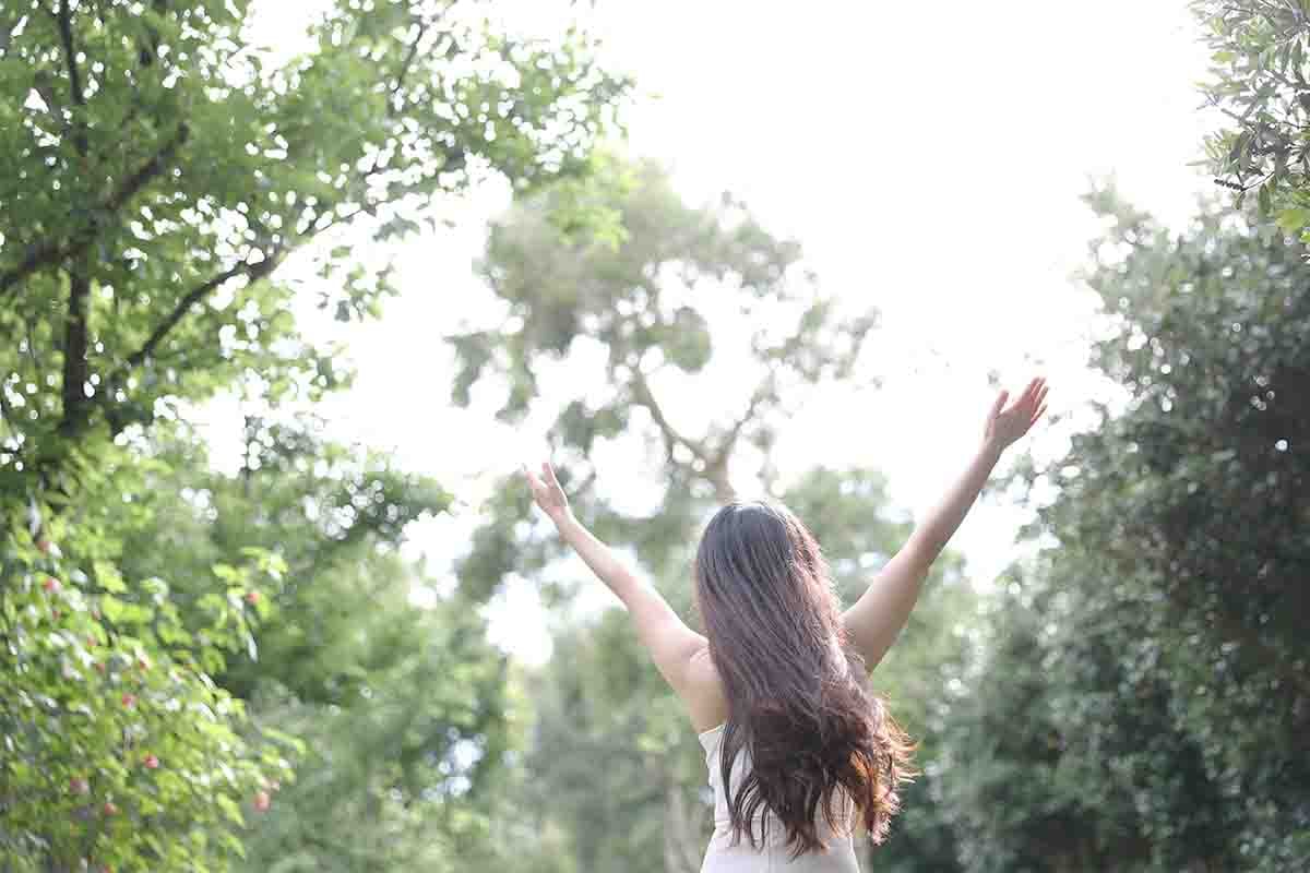 woman raising hands in nature