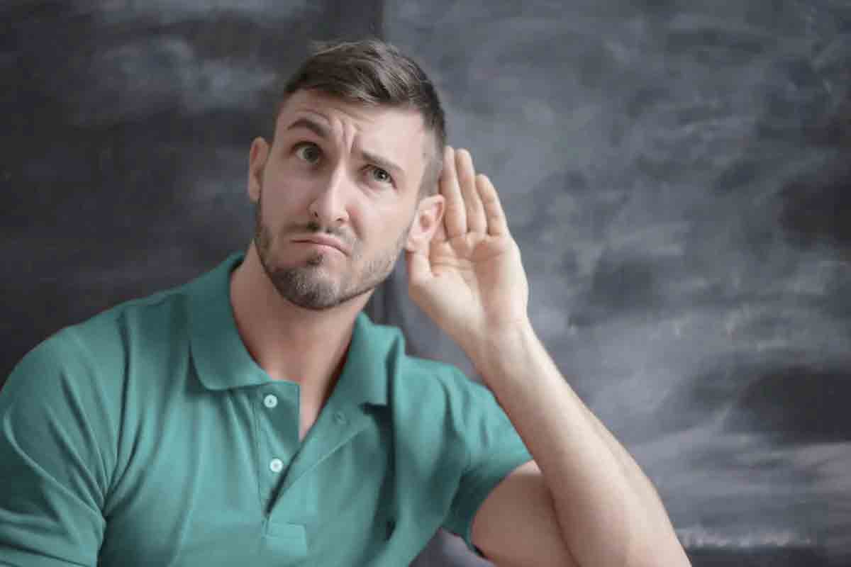 A man putting hands by ear because he cannot hear well